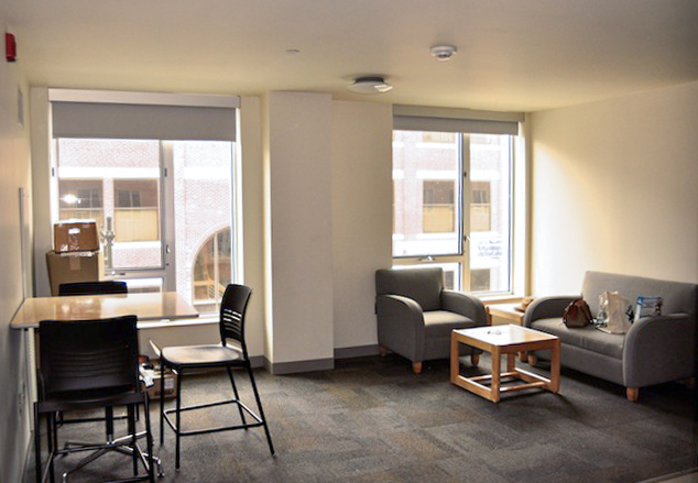 A room with large windows, seating area and small table and chairs